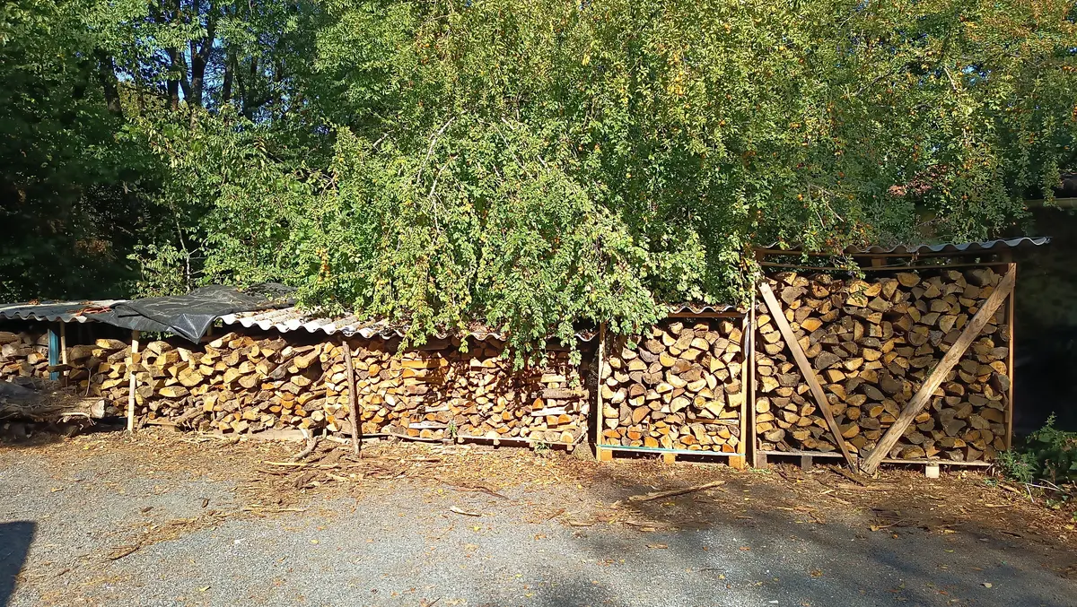 Réserve de bois de chauffage soigneusement empilé sous des abris, prête pour alimenter la cheminée